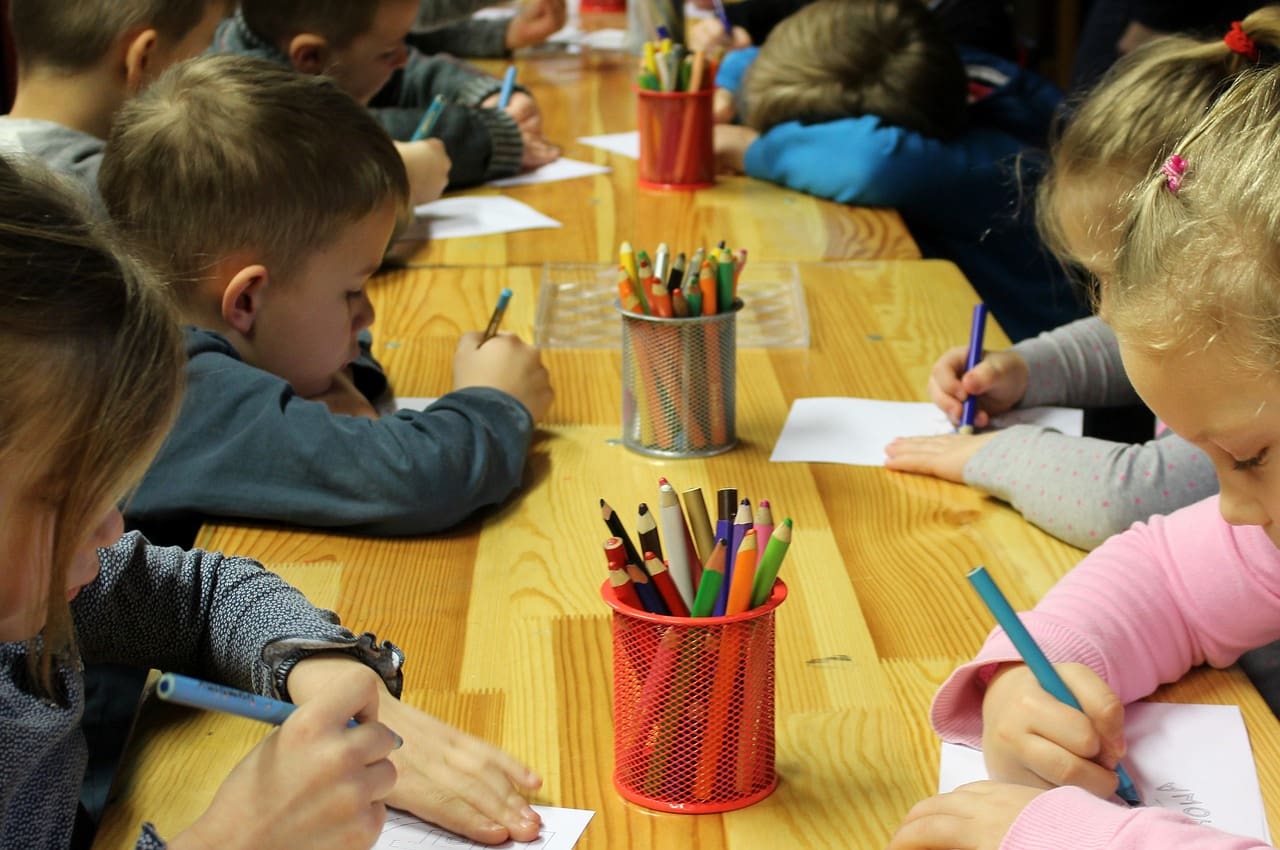 children drawing with colored pencils in class